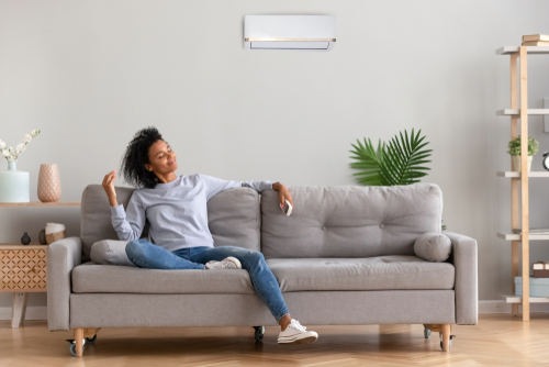 woman enjoying cool refreshing air conditioning on the couch at home