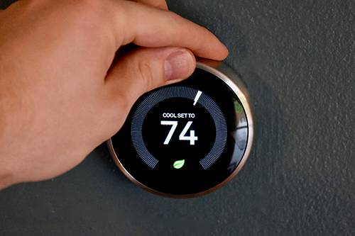 HVAC technician setting smart thermometer to 74 degrees