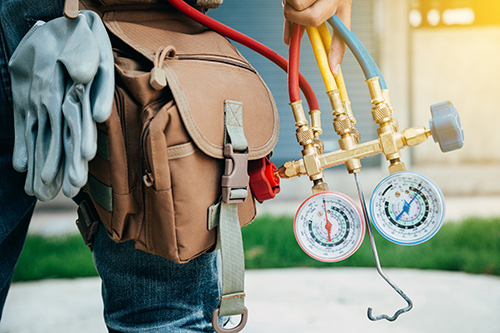 HVAC contractor holds meter for Air Conditioning repair