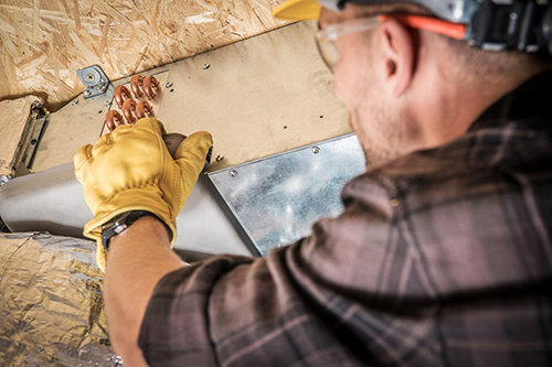 HVAC contractor checks air conditioning duct work for maintenance 